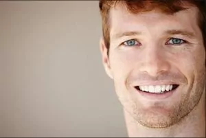 A young man smiling with picture perfect teeth from whitening treatments.