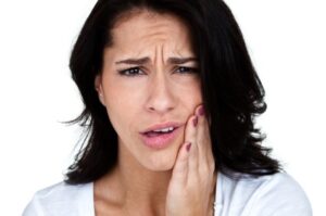 A young woman clutching her jaw in need of a root canal in Salt Lake City.